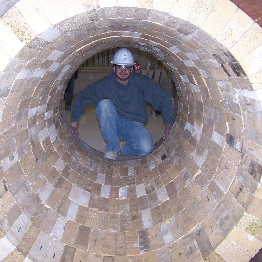 An Empire Solutions team member poses inside of a brick furnace.